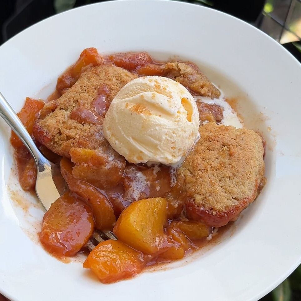Skillet peach cobbler with a golden snickerdoodle cookie crust - Hungry Mockingbird